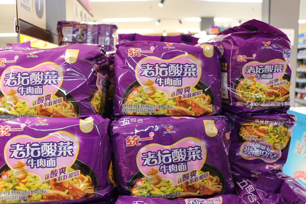 a pile of purple bags of food on a store shelf