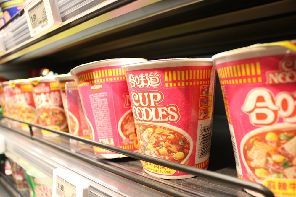 three cups of soup on a shelf in a store