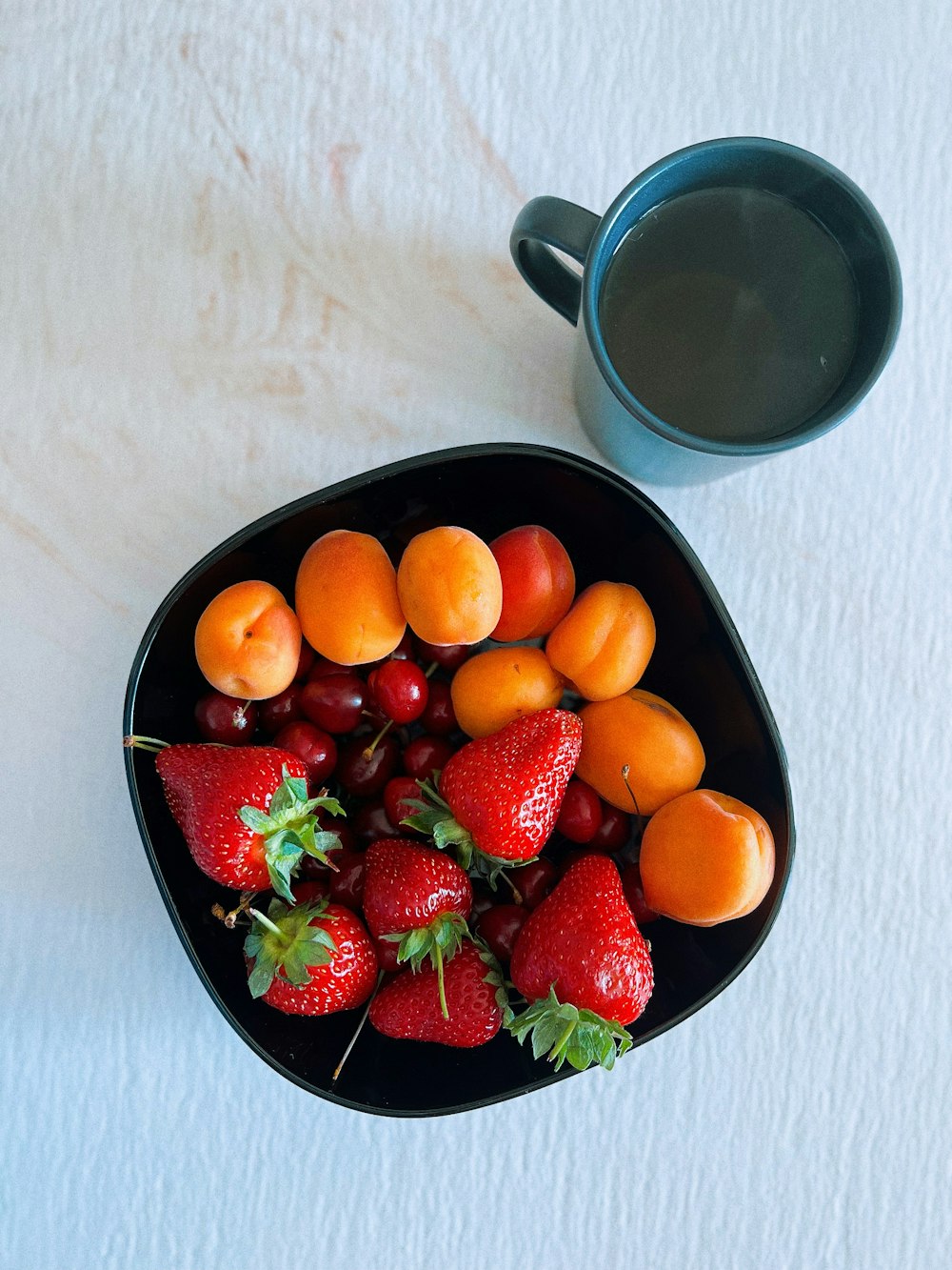 a bowl of fruit and a cup of coffee