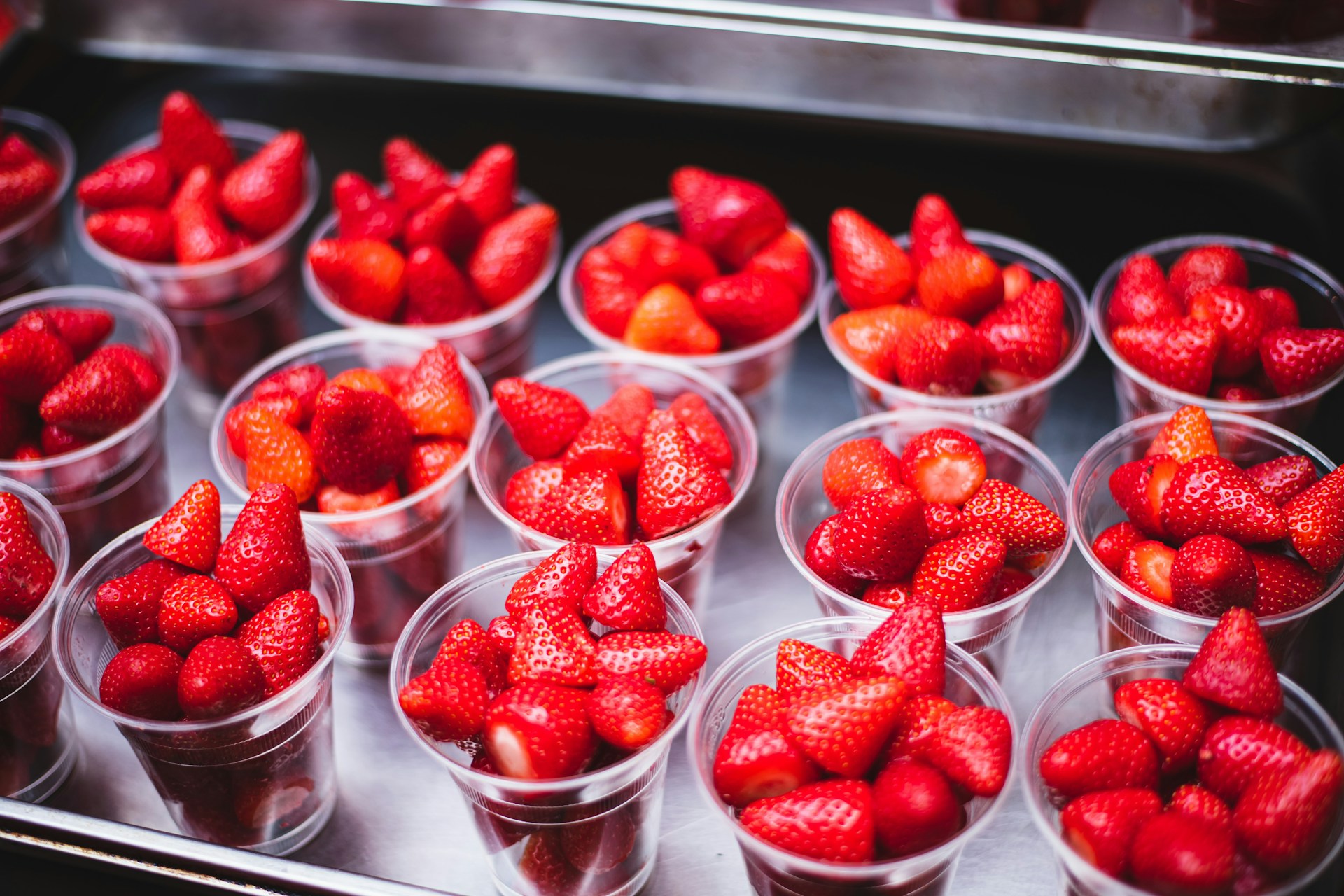 a bunch of strawberries in plastic cups on a tray