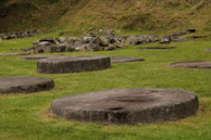 A circle of stones and candles set on earth, hinting at a sacred gathering space.