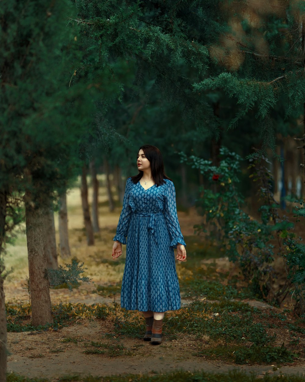 Une femme en robe bleue marchant dans une forêt