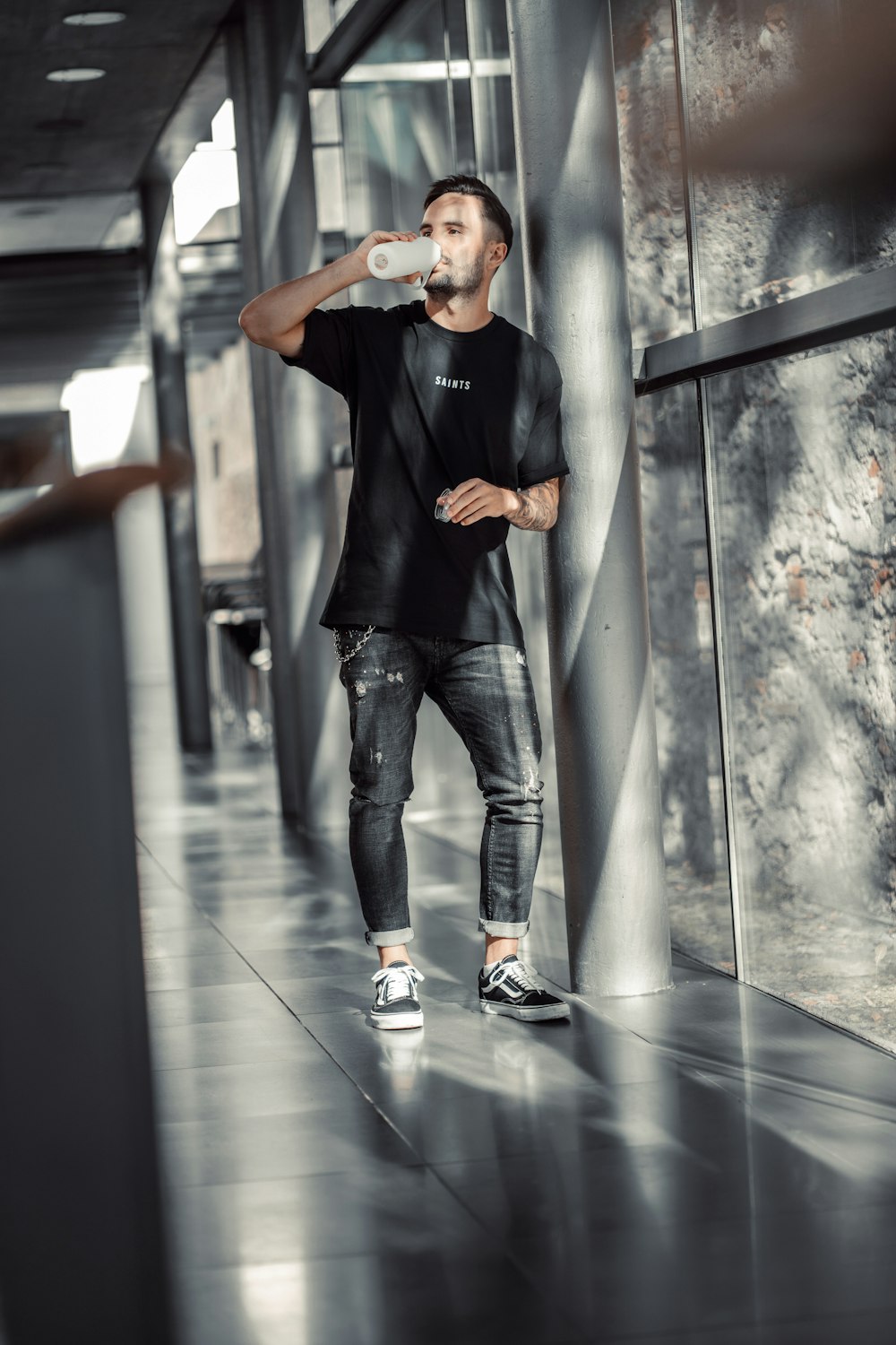 a man standing in a hallway drinking from a bottle