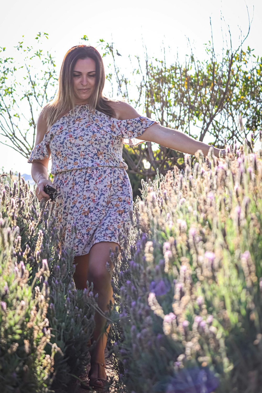 a woman walking through a field of lavender flowers