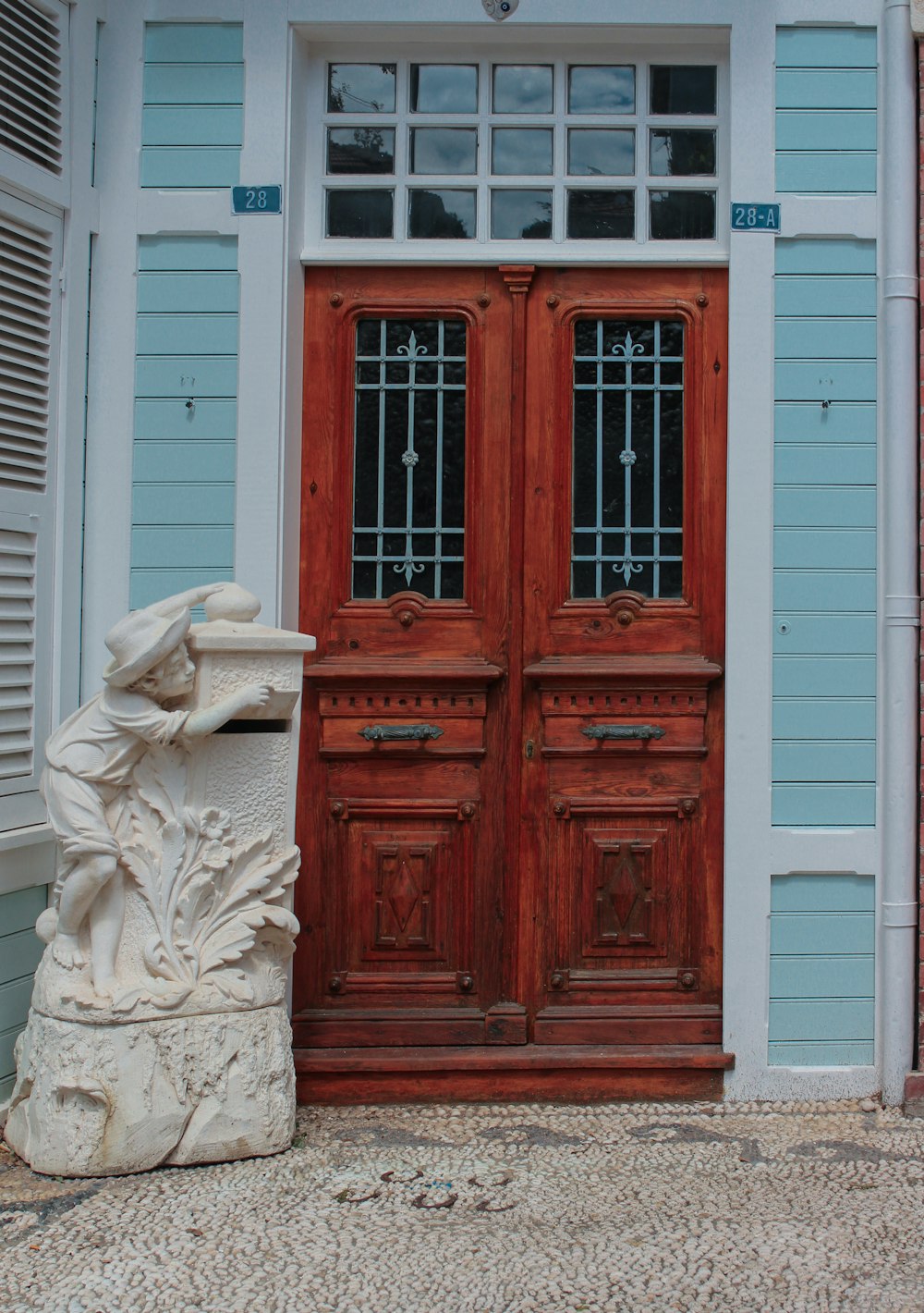 une statue assise devant une porte en bois