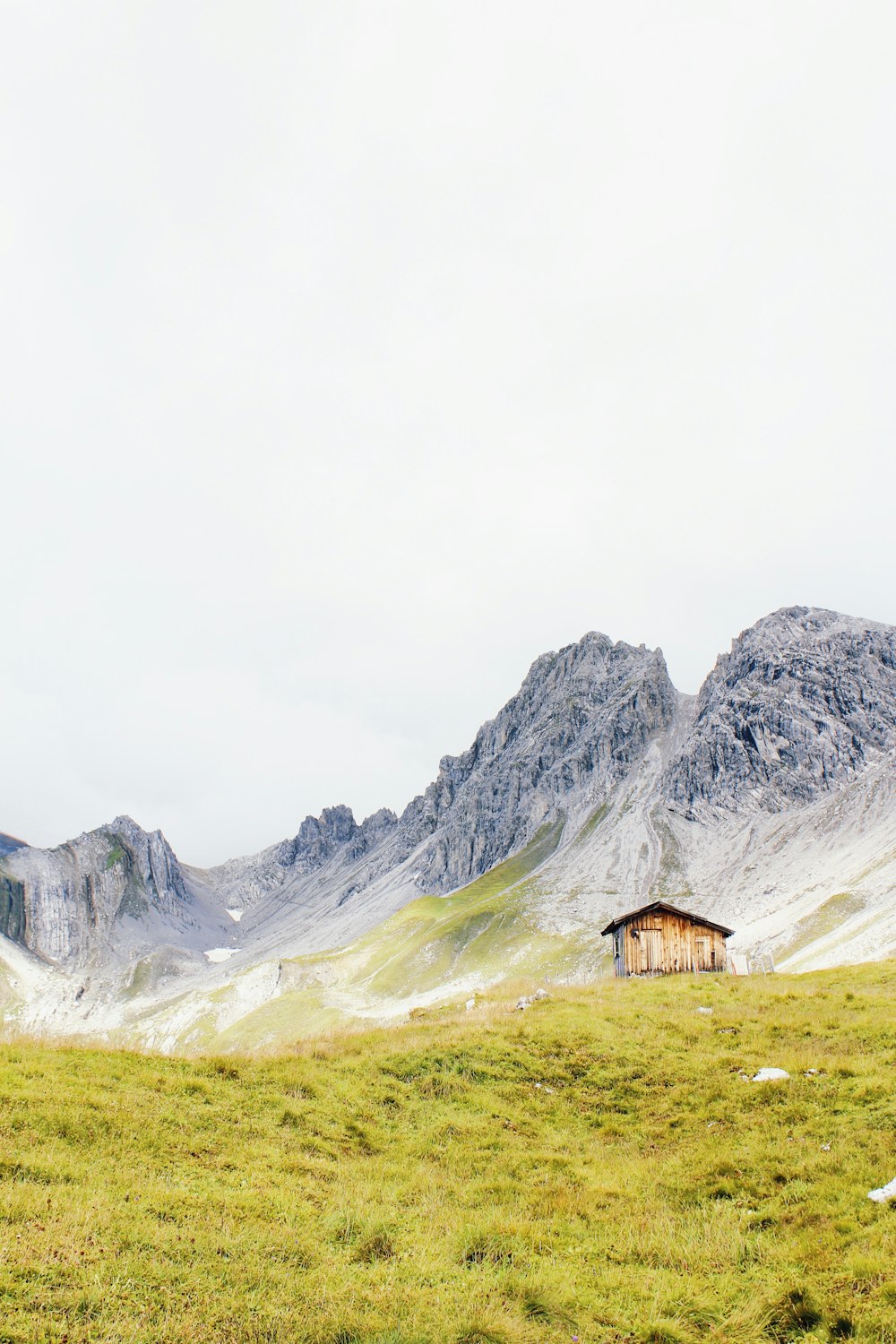 a grassy field with a small cabin in the middle of it