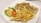 A white plate containing crispy fried chicken strips, a serving of golden French fries, and a side salad with shredded cabbage, lettuce, sliced cucumber, and a tomato slice topped with a dollop of creamy dressing.