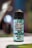 A bottle of e-liquid is prominently displayed, featuring a label with the text 'Ultimate E-Liquid Menthol Original.' The label is decorated with images of mint leaves and an icy background, suggesting a cooling menthol flavor. The bottle cap is black, and the background is blurry, with bokeh lights, creating a focused and isolated view of the product.