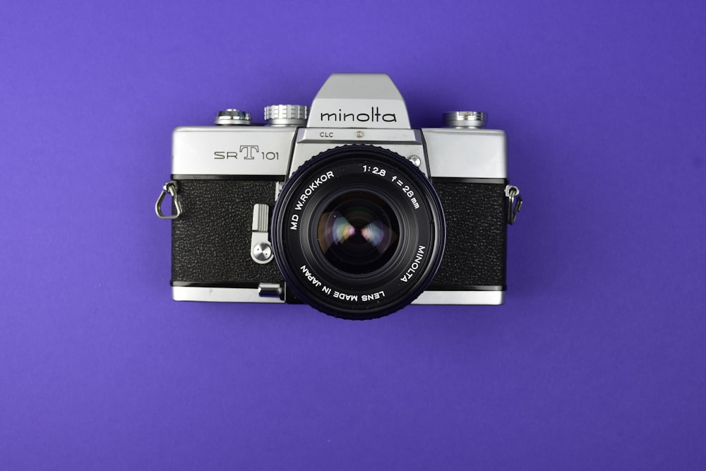 a camera on a purple background with a black lens