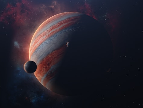 A large gas giant planet with swirling, colorful bands is prominently displayed, partially shadowed, with two smaller celestial bodies nearby. The background consists of a starry sky with nebula-like clouds.