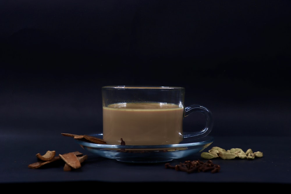 a glass cup filled with liquid next to a pile of nuts