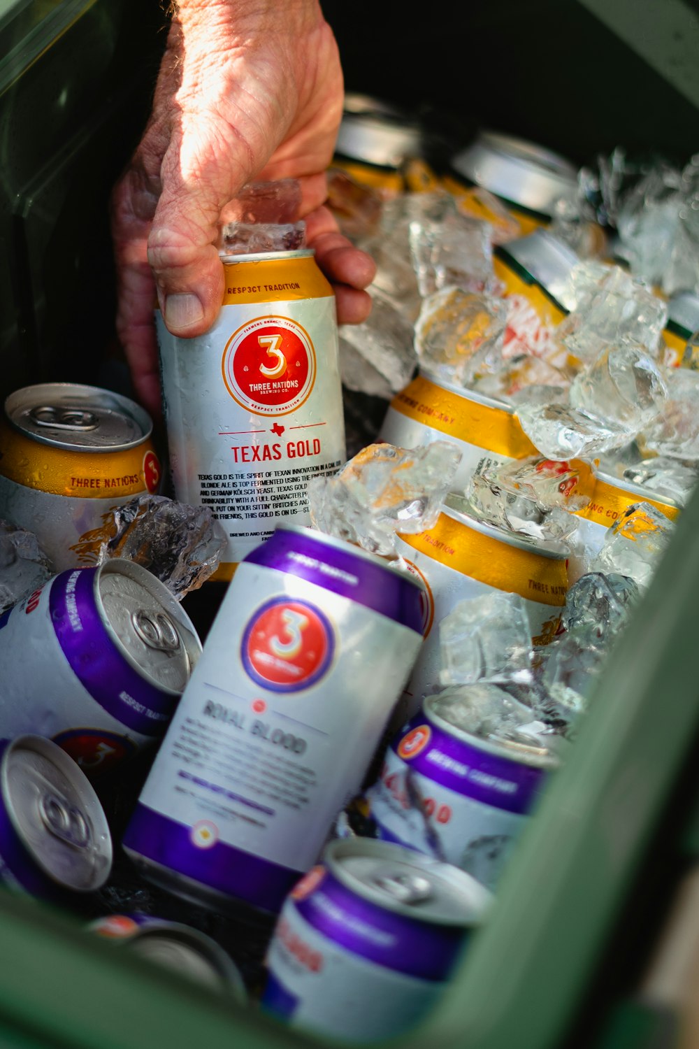 a person holding a can of beer in a trash can