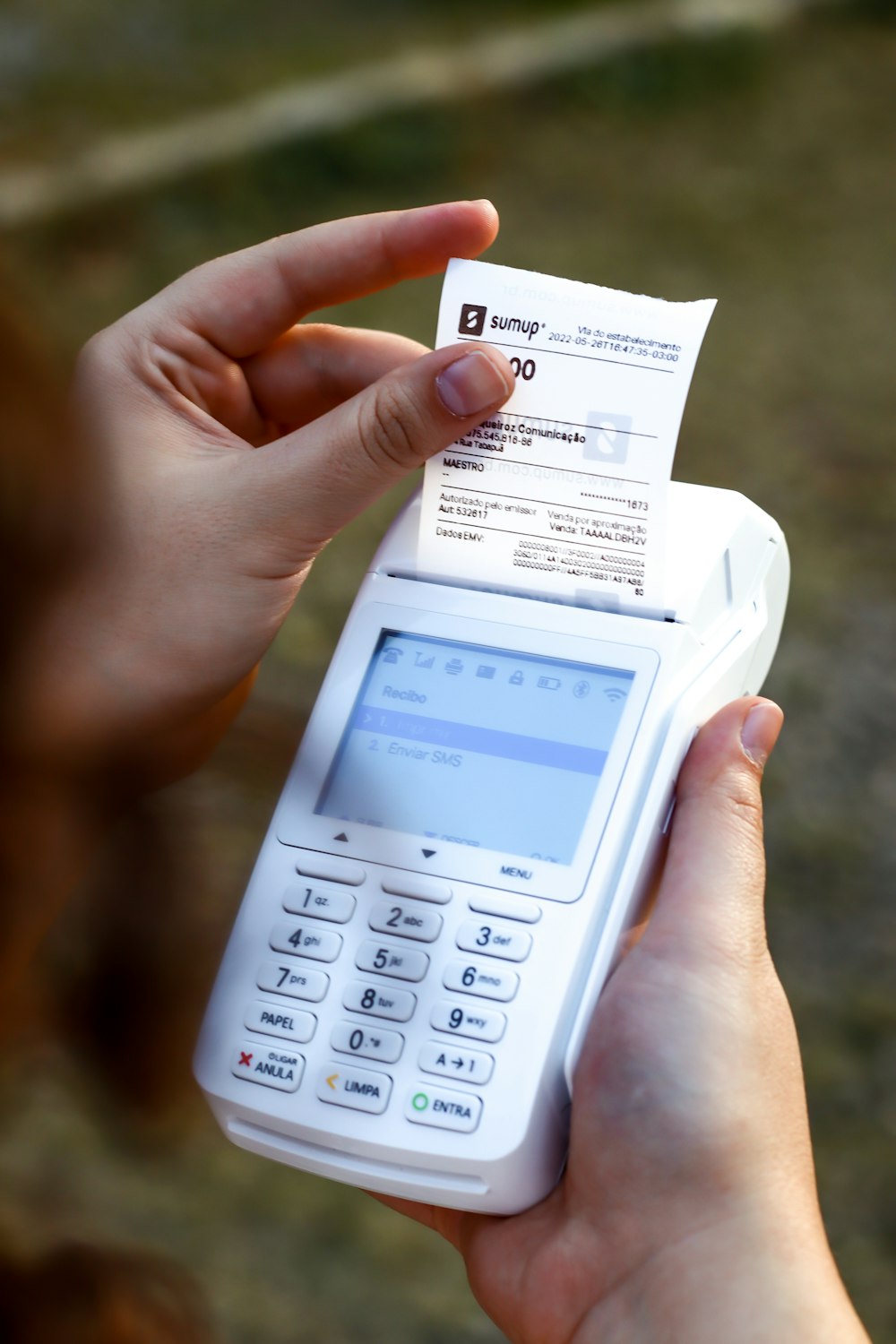 una persona que sostiene un teléfono celular y un recibo