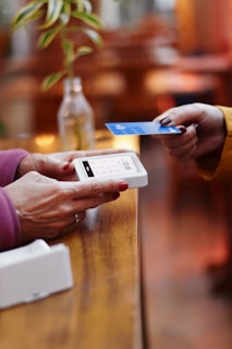 two people exchanging a credit card at a table