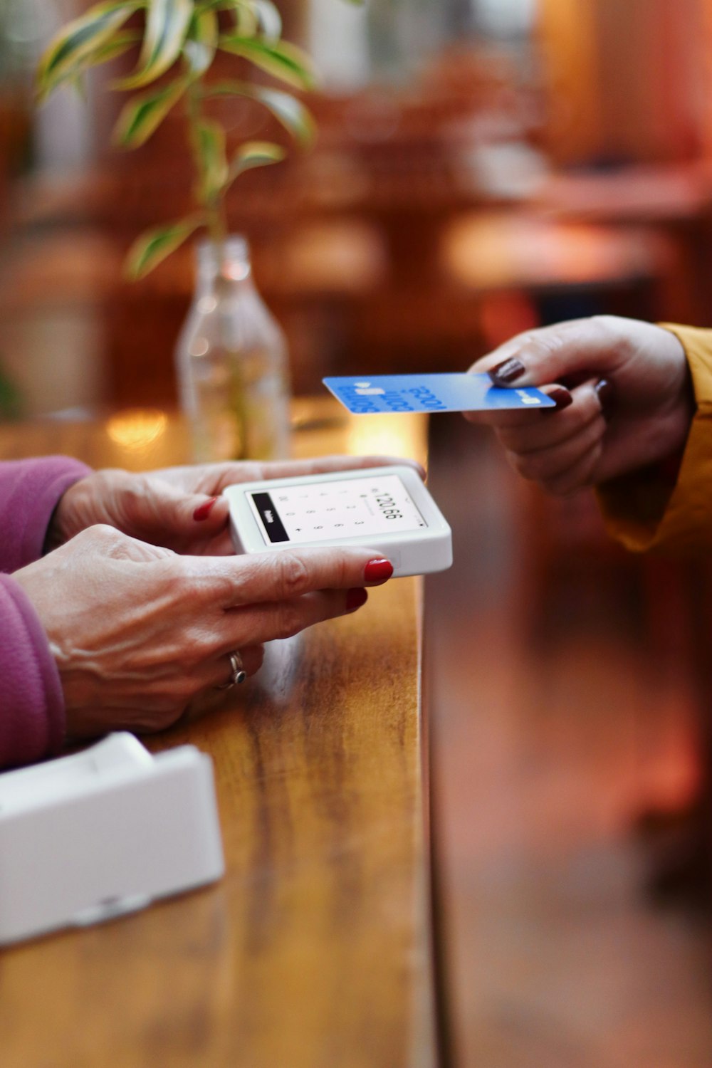 two people exchanging a credit card at a table