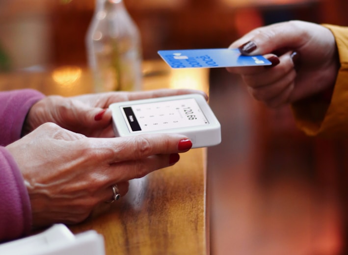 two people exchanging a credit card at a table