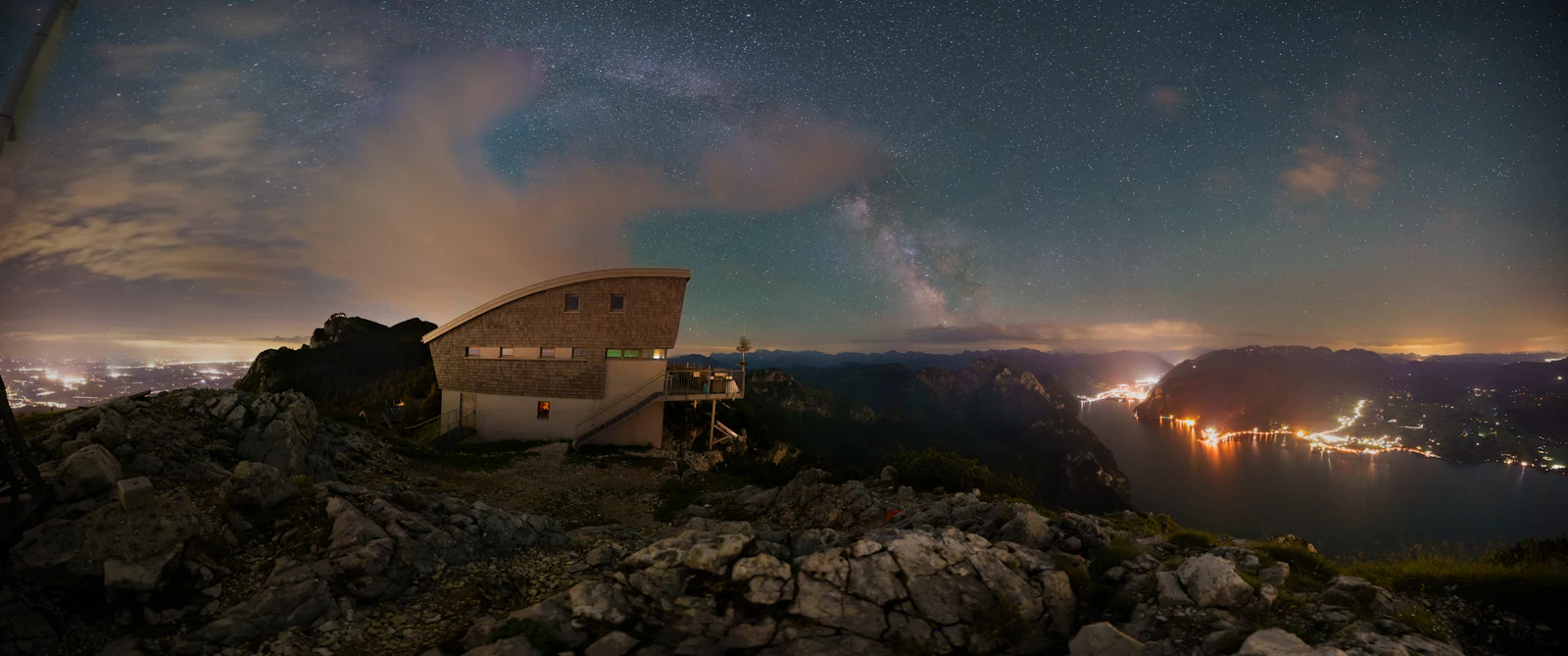 Photograph of The Traunstein plateau huts beneath a clear night sky, with Gmunden's lights far below beside Traunsee.