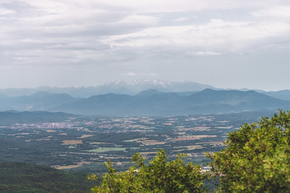 a view of a valley and mountains from a hill