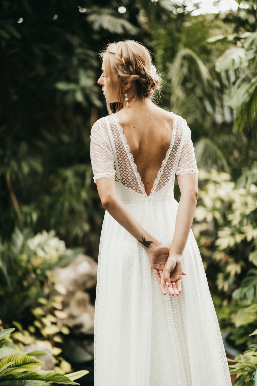 a woman in a white dress standing in a forest