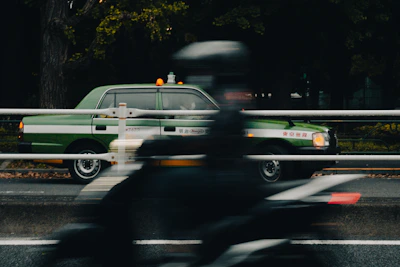 A sleek green taxi parked outside T.F. Green Airport with a clear view of the terminal in the background.