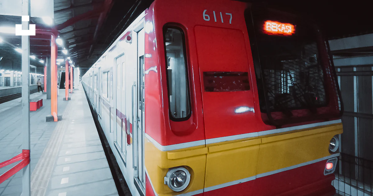 A red and yellow train pulling into a train station photo – Free ...