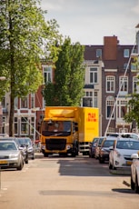 a yellow truck driving down a street next to tall buildings