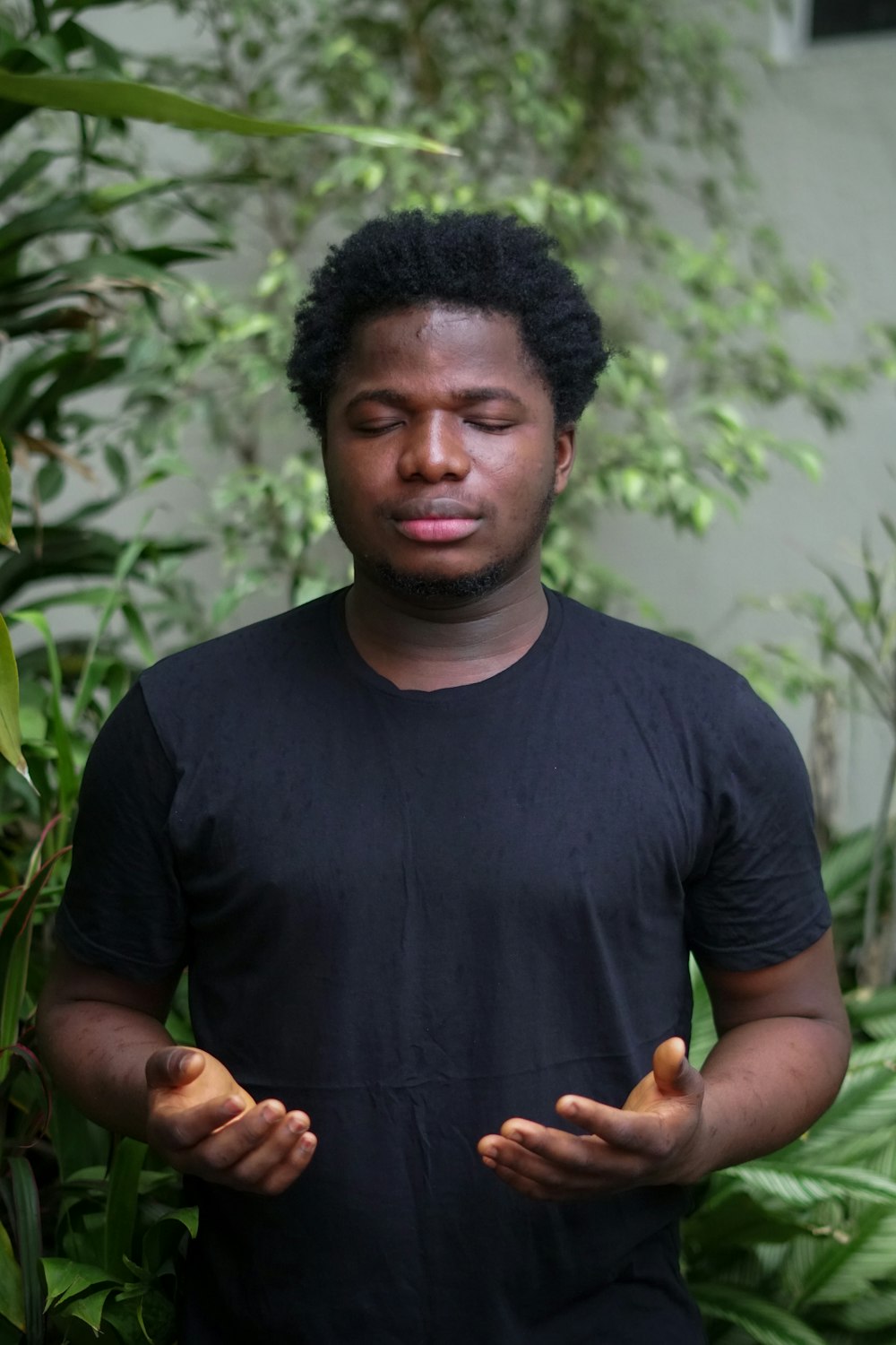 a man standing in front of a bush with his eyes closed