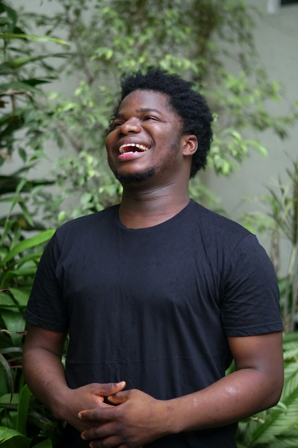 a man laughing while standing in front of plants