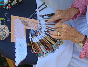 an older woman holding a bunch of knitting needles