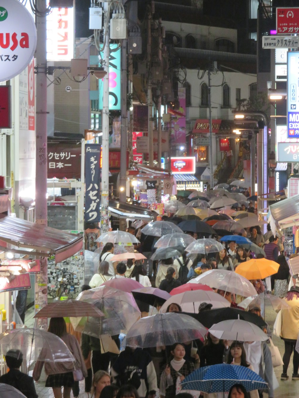 Una folla di persone che camminano lungo una strada tenendo ombrelli