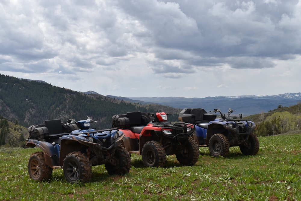 a group of four atvs parked on top of a lush green hillside