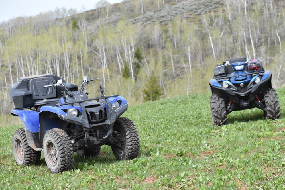 two atvs are parked in a grassy field