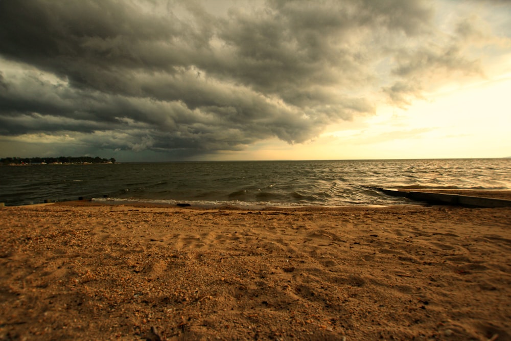 a cloudy day at the beach with a surfboard in the foreground