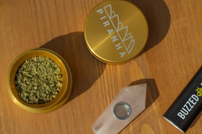 A sleek grinder and lighter set displayed against a backdrop of green leaves and soft natural light.