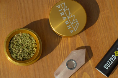 A sturdy metal grinder open to reveal finely ground herbs inside.