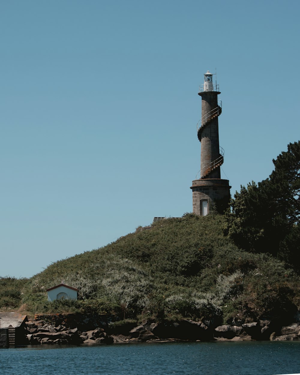 a lighthouse on top of a hill next to a body of water