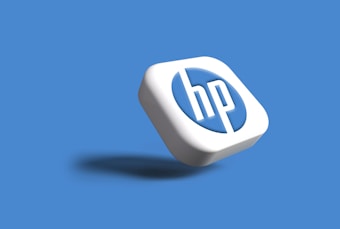 A three-dimensional, stylized version of the HP logo appears on a solid blue background. The logo is displayed in white and blue colors, with a subtle shadow cast beneath it, giving a floating effect.