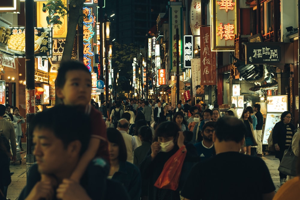 Una multitud de personas caminando por una calle por la noche