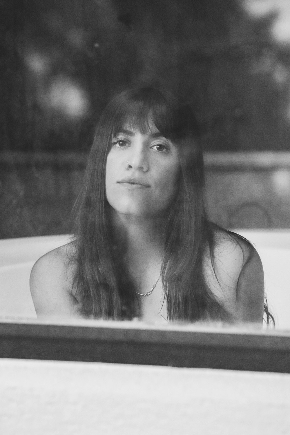 a woman sitting in a bathtub looking out the window