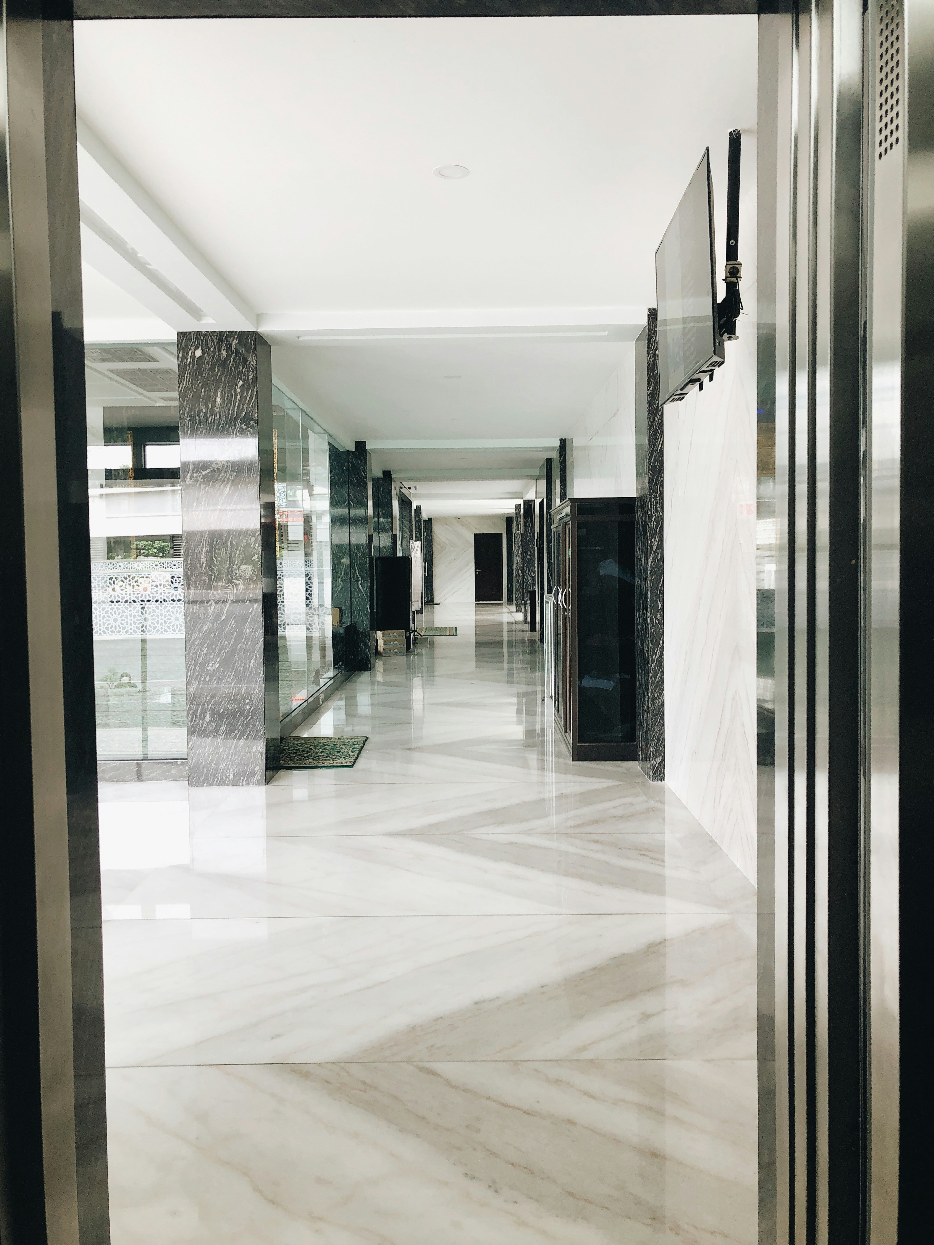 Elegant luxury home hallway with seamless high-gloss white epoxy floor, marble-like finish reflecting grand staircase and natural light
