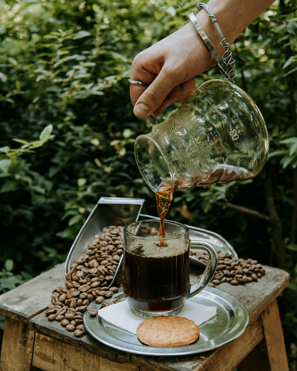 a person pours coffee into a glass mug