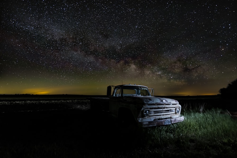 a truck parked in a field under a night sky filled with stars