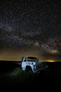 A weary trucker taking a moment to rest beside his rig under a vast open sky.