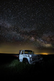 A weary trucker taking a moment to rest beside his rig under a vast open sky.
