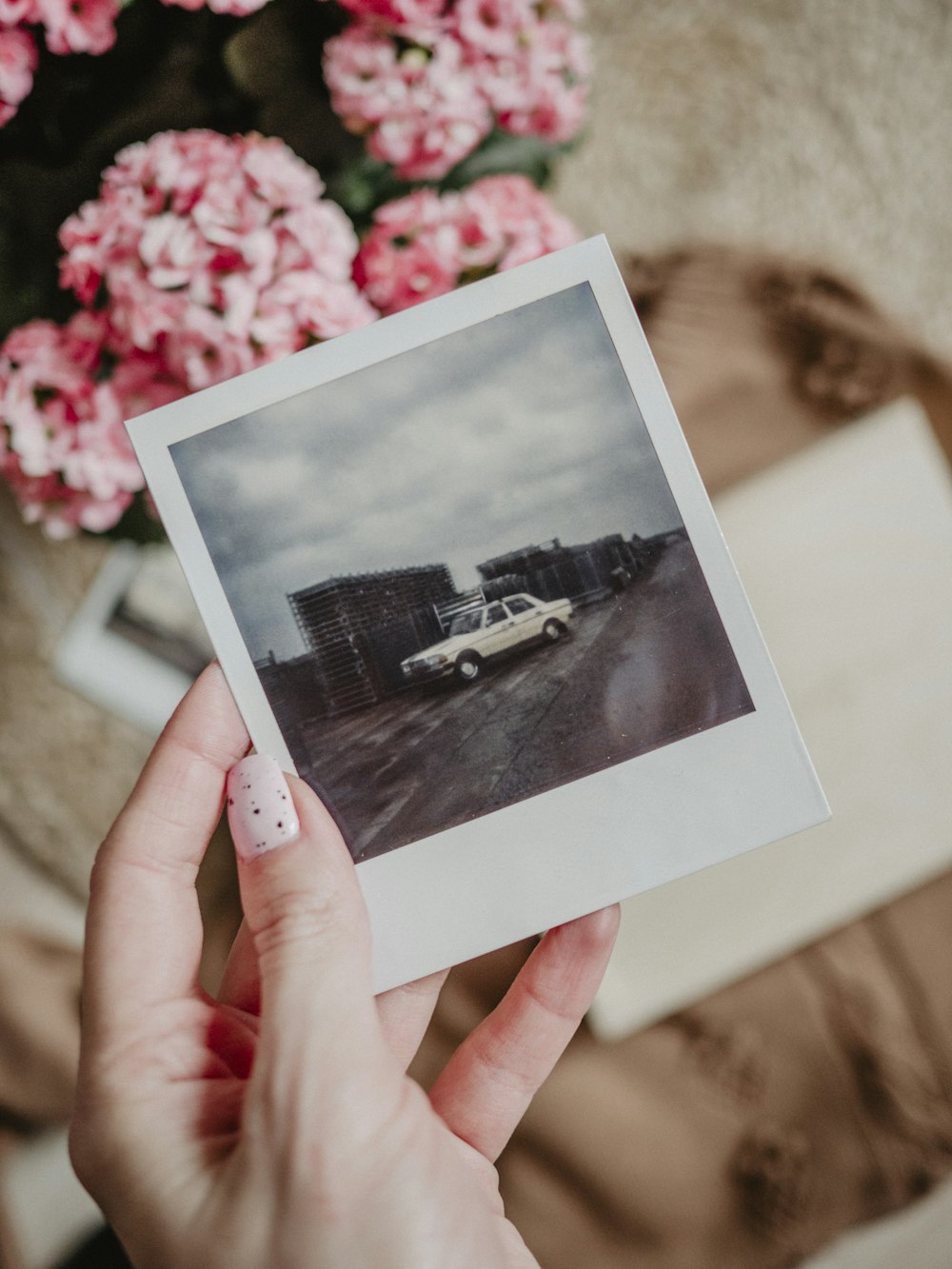 a person holding a polaroid with a picture of a car