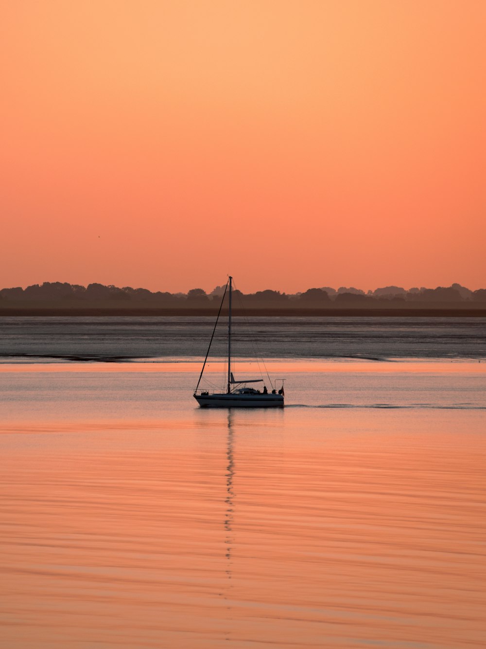 una barca a vela in acqua al tramonto