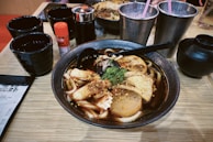 A close-up of steaming hot spicy noodle soup with red chili flakes.