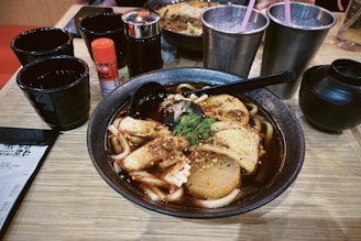 A close-up of steaming hot spicy noodle soup with red chili flakes.