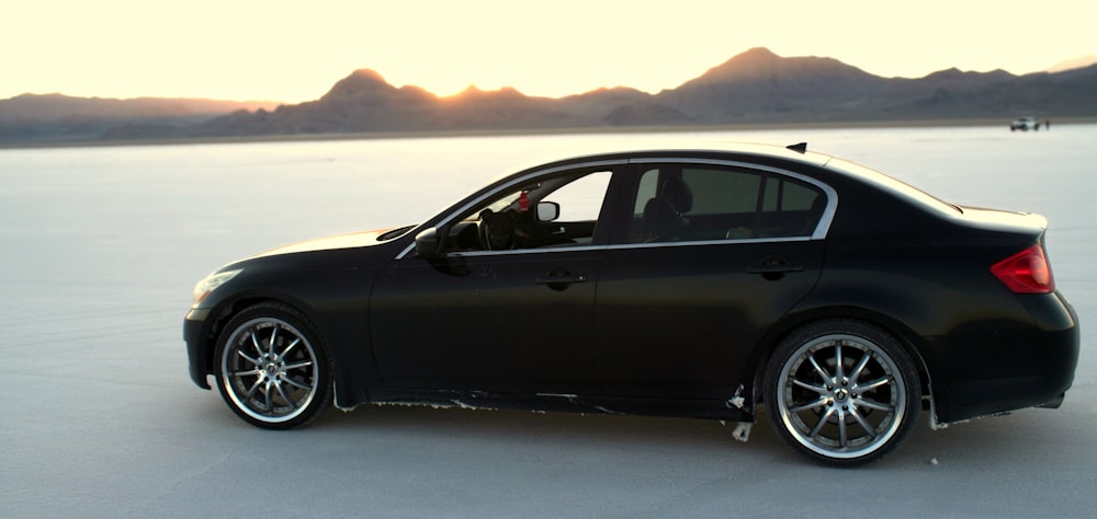 a black car is parked in the middle of the desert