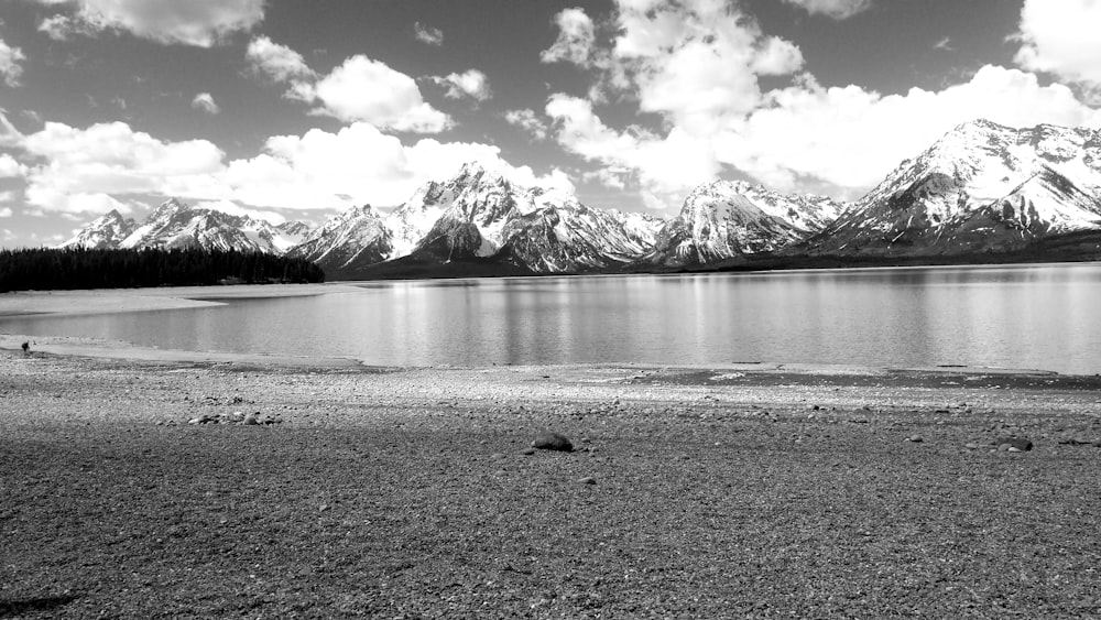 a black and white photo of a lake with mountains in the background